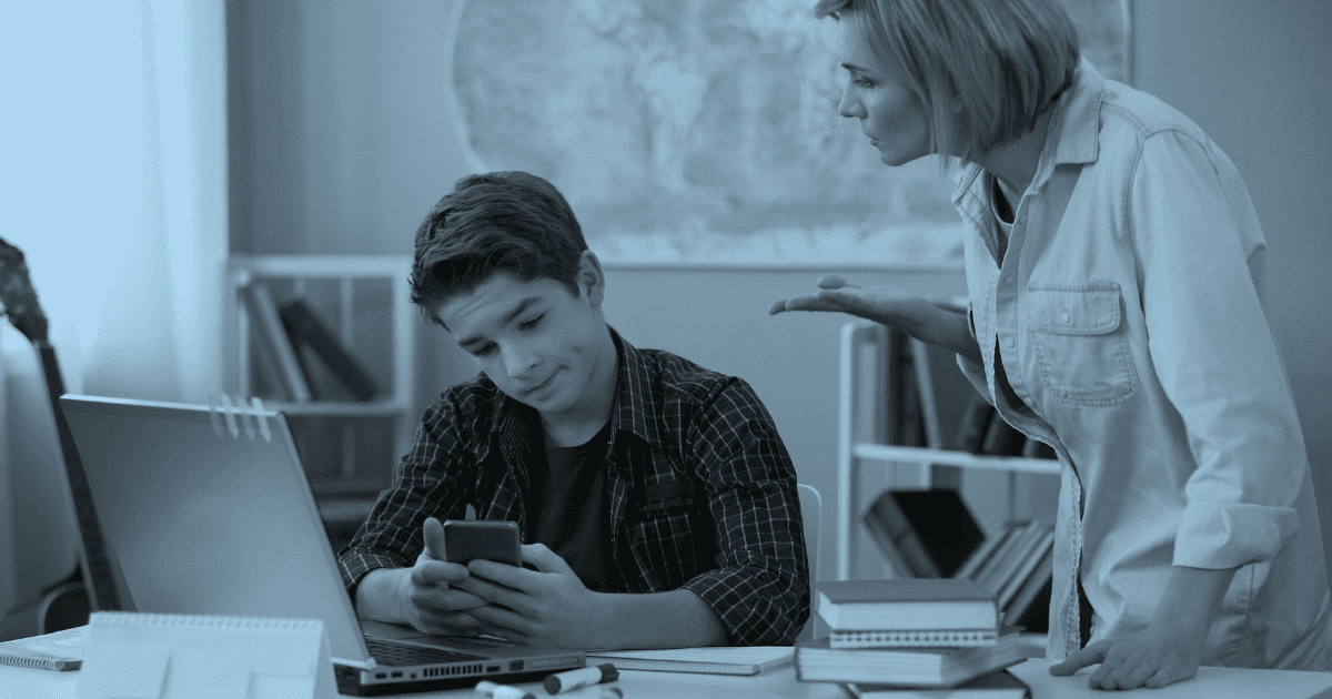 photo of mom talking to her indifferent son who is in front of a laptop and busy looking at his phone